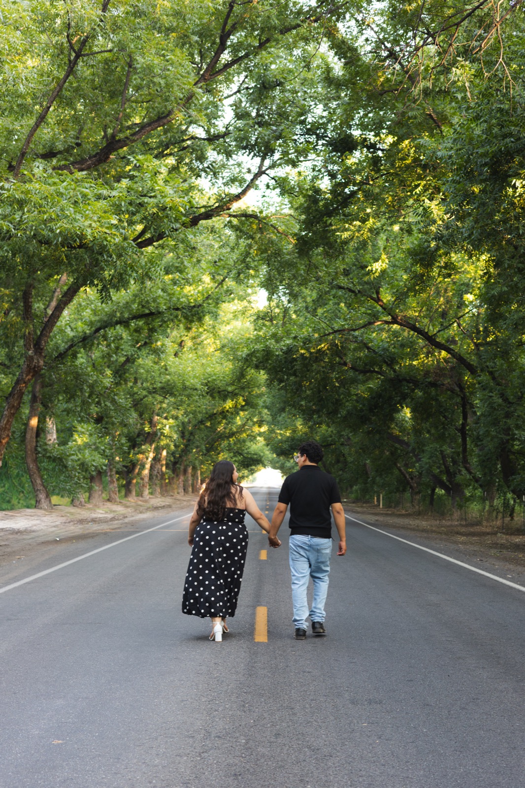A couple walking together beneath green trees