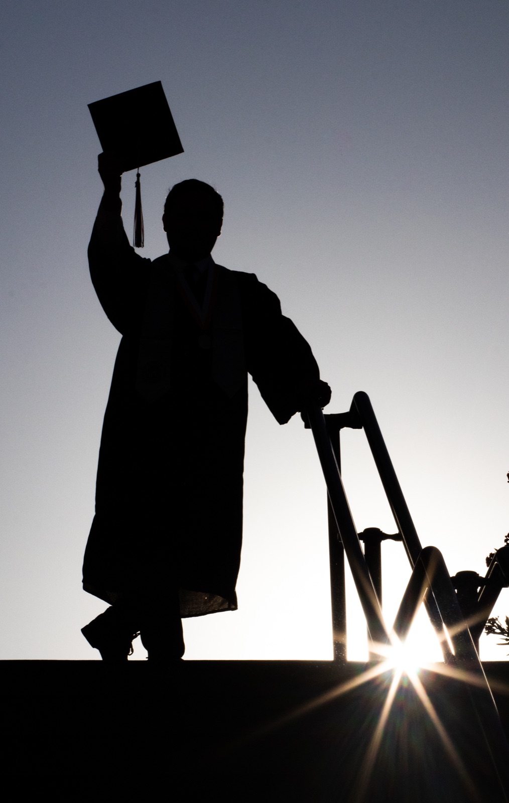 A graduate silhouetted against the setting sun