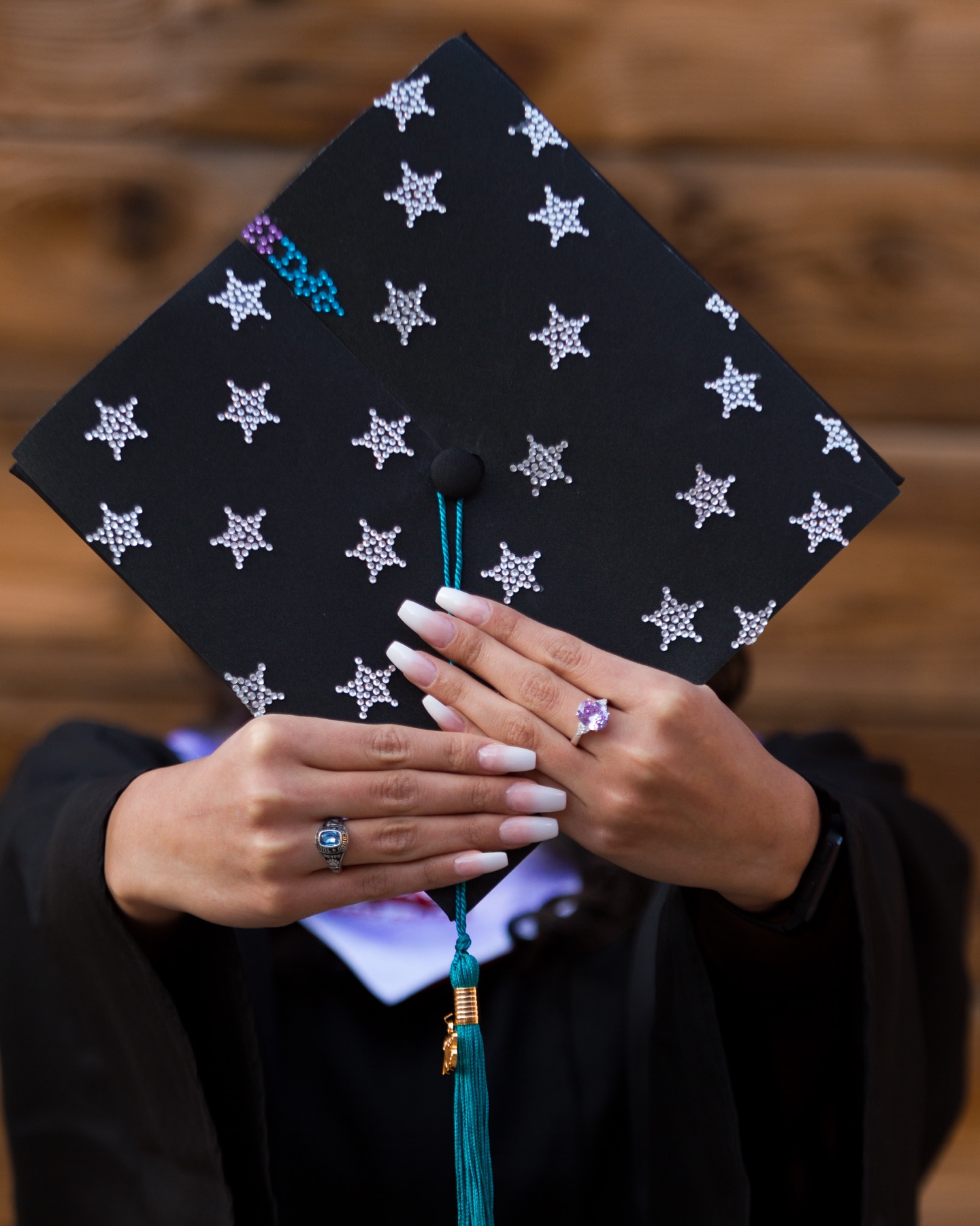 A graduate holding a cap decorated with silver stars