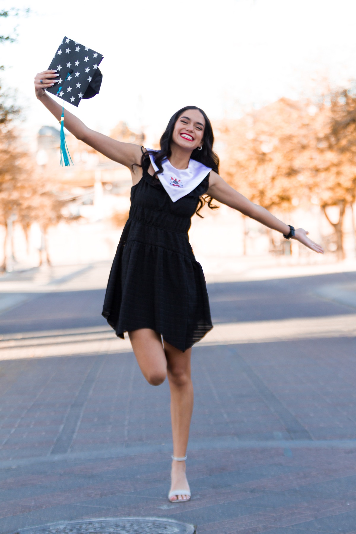 Katy celebrating graduation with her cap held in the air